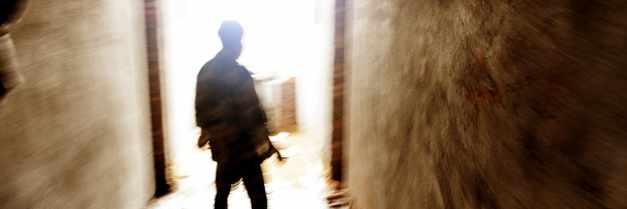 When Your Loved One Is Experiencing Psychosis A lonely person standing in a narrow passage