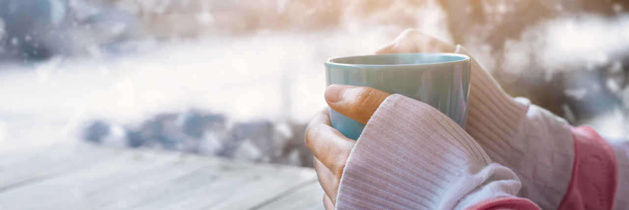 11 Things I Love About Winter, Despite Depression Side view of female hand holding hot cup of coffee in winter - Photo in vintage color image style.