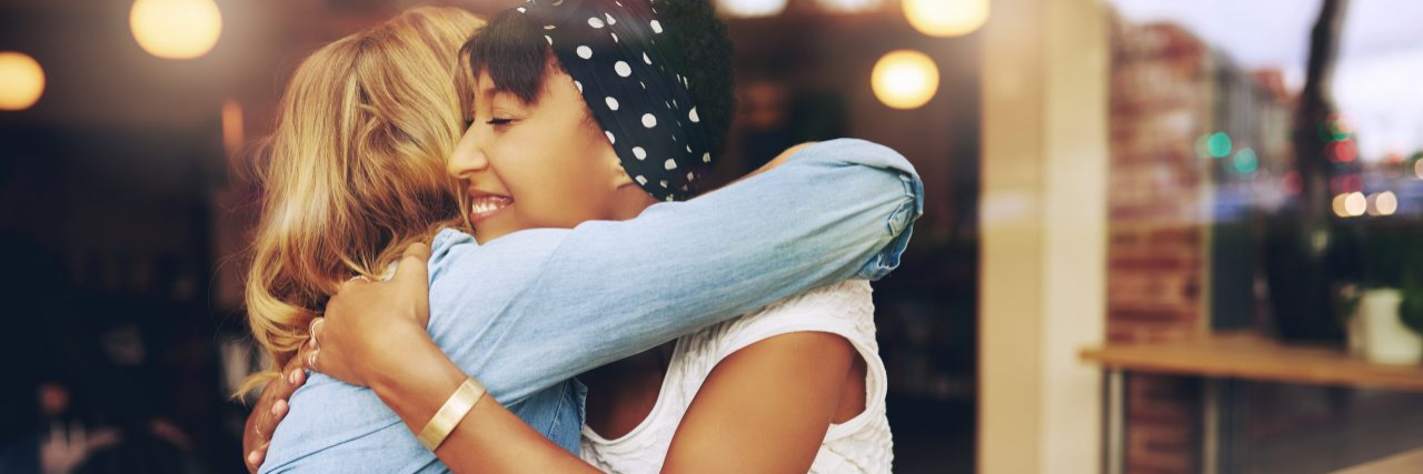19 Things People With Chronic Illness Want Their Friends to Know Two multi ethnic friends embracing as they sit in a coffee shop