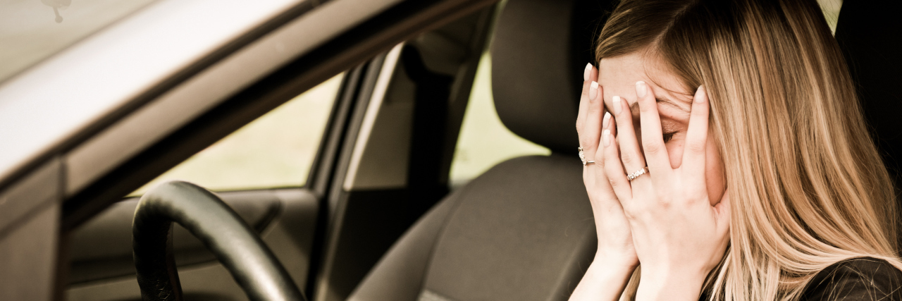 Learning to Drive as Someone on the Autism Spectrum Young woman with hands on eyes sitting stressed in car.