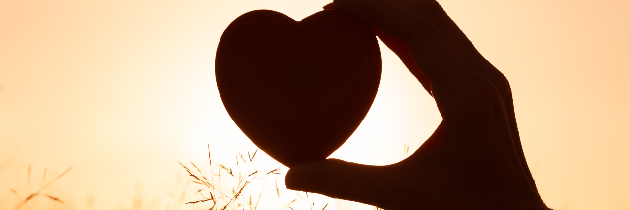 Here's What You Should Include in a Chemo Care Package Hand holding heart against beautiful setting.