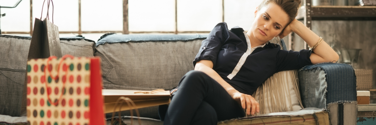 Having Trouble Holiday Shopping With Social Anxiety woman looking stressed after shopping sitting on sofa