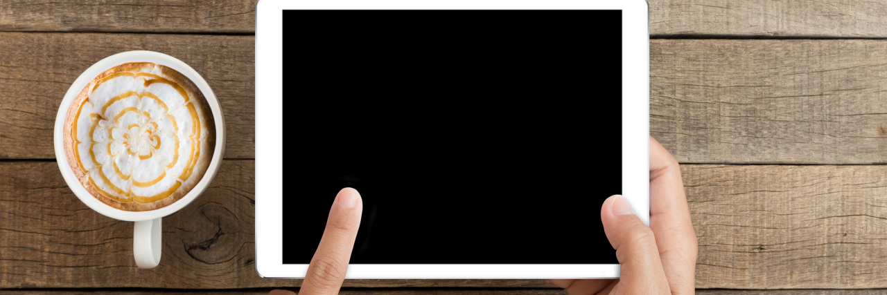 Fun and Creative Apps to Try When Your Pain Is Overwhelming Someone holding an iPad or similar device, with a cup of coffee next to them.