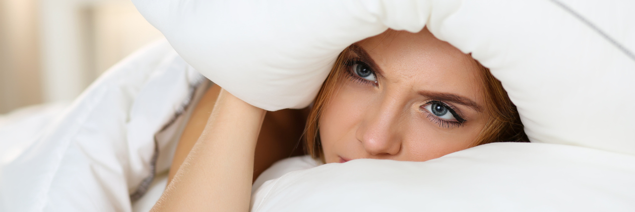 Why It Doesn't Matter When OCD Rituals Are 'Ridiculous' young woman lying in bed covering head with pillow