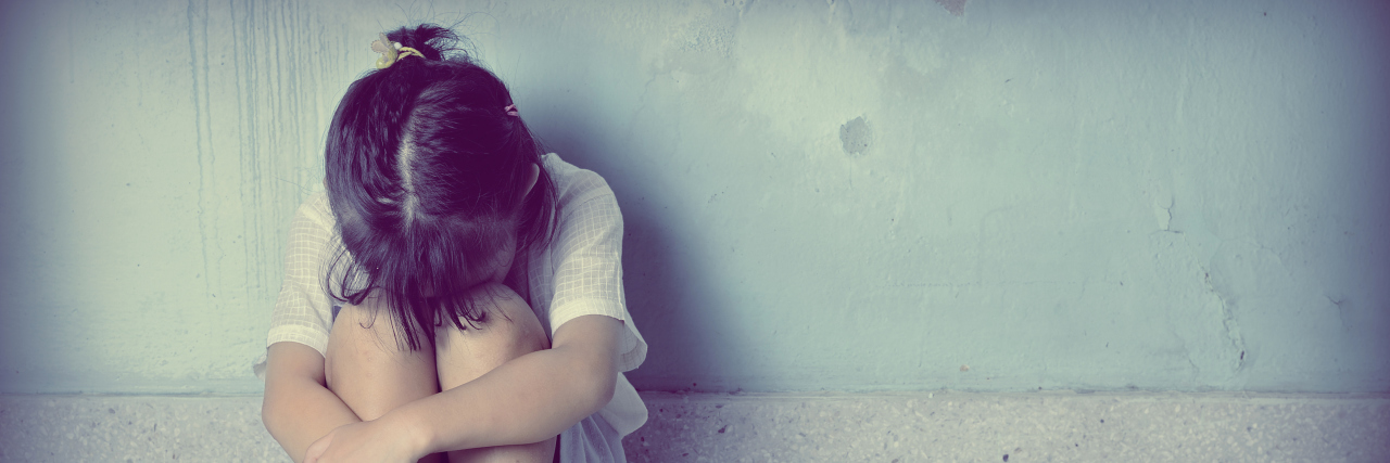 When You've Grown Up With Anxiety sad and depressed little girl sitting near the wall