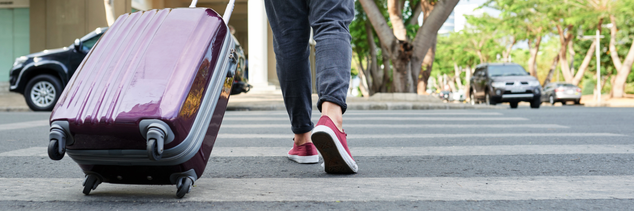 What Living Abroad With Depression Is Like Cropped image of traveler with big suitcase crossing road