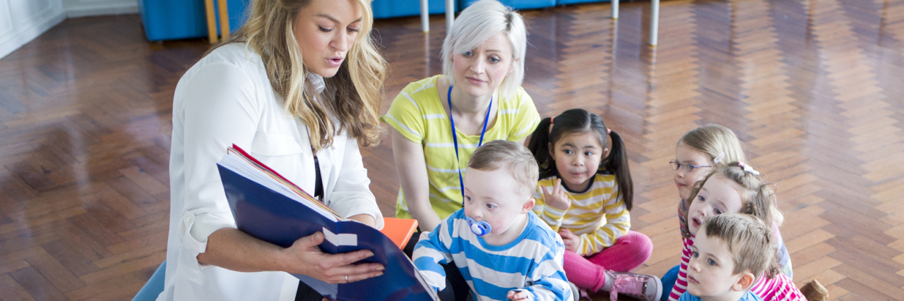 Promoting Real Inclusion for Special Education Students Children surrounding teacher reading a book.