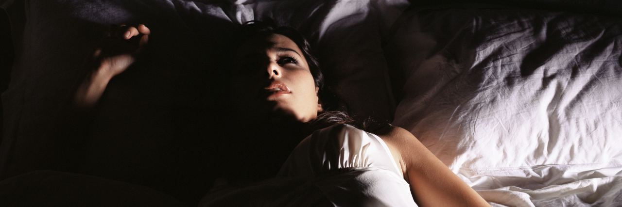 Struggling With Insomnia at Night Due to Chronic Pain woman lying awake in bed at night