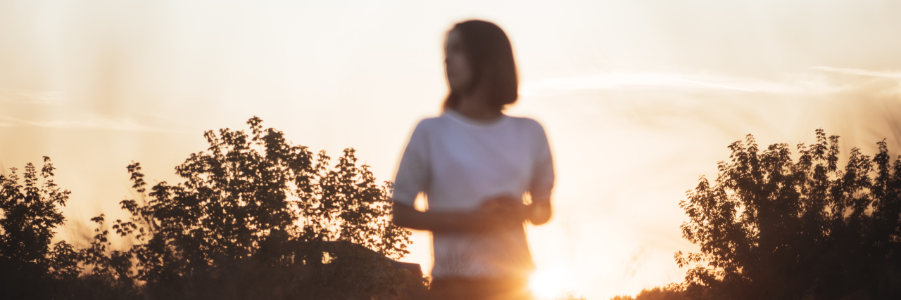When I Finally Learned How to Accept Help From My Therapist Young attractive brunette standing in the sunset summer field, contemplating. Photo with unusual focus