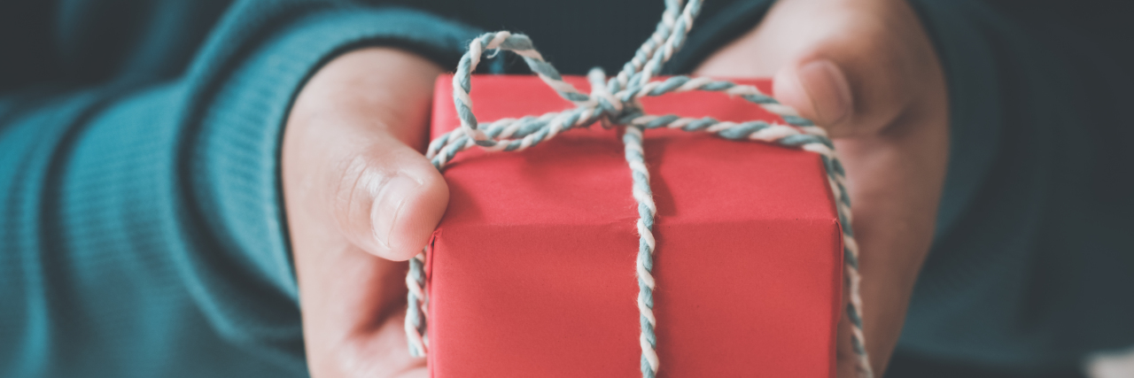 Woman hands holding a Christmas gift red box. Christmas presents and New Year. Handmade.