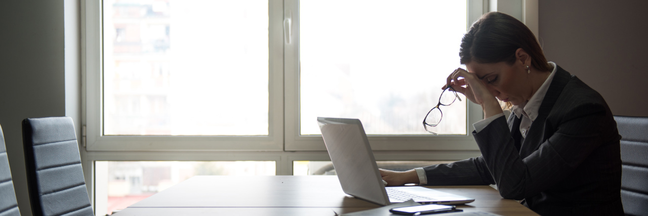 When You're Afraid of Telling Your Work About Your Mental Illness Businesswoman sitting in a office worried about a problem on her laptop, tired and under the stress