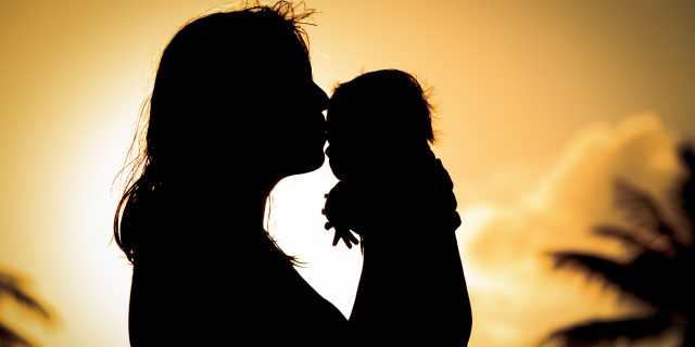 loving mother and kissing little baby play at sunset