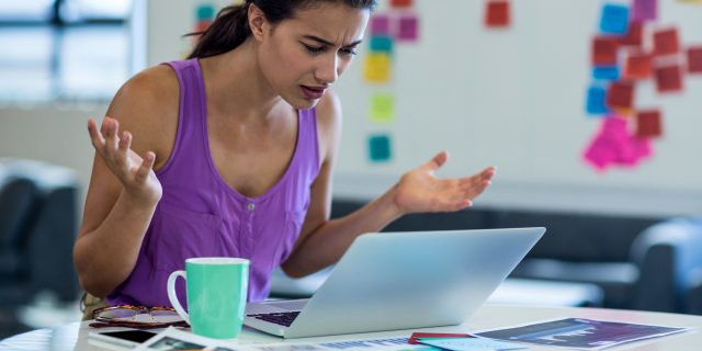 Young woman looking surprised while using the laptop in the office