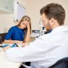 frustrated woman in doctor's office while doctor fills in form