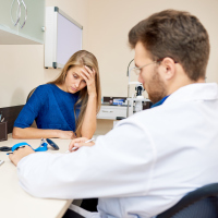 frustrated woman in doctor's office while doctor fills in form