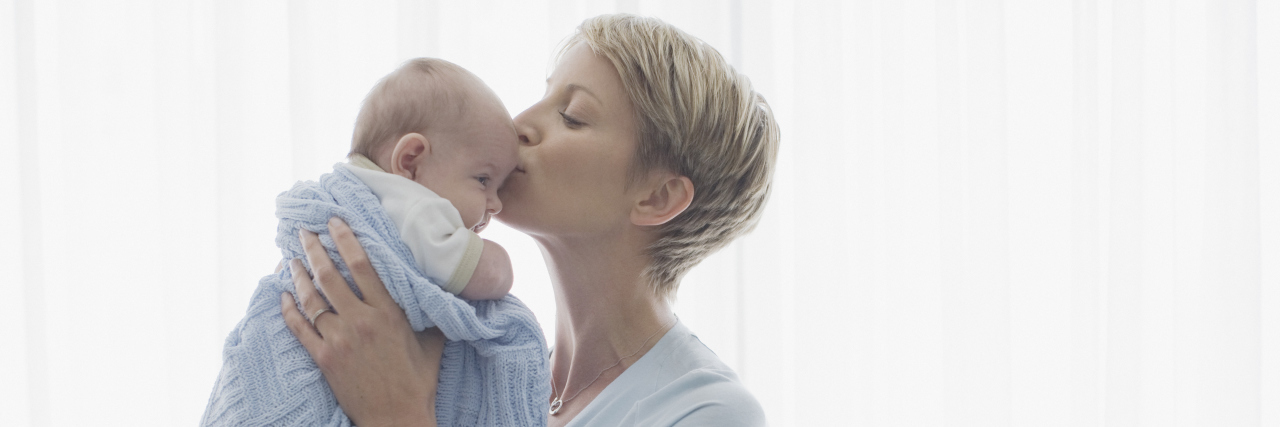 mother kissing her newborn baby