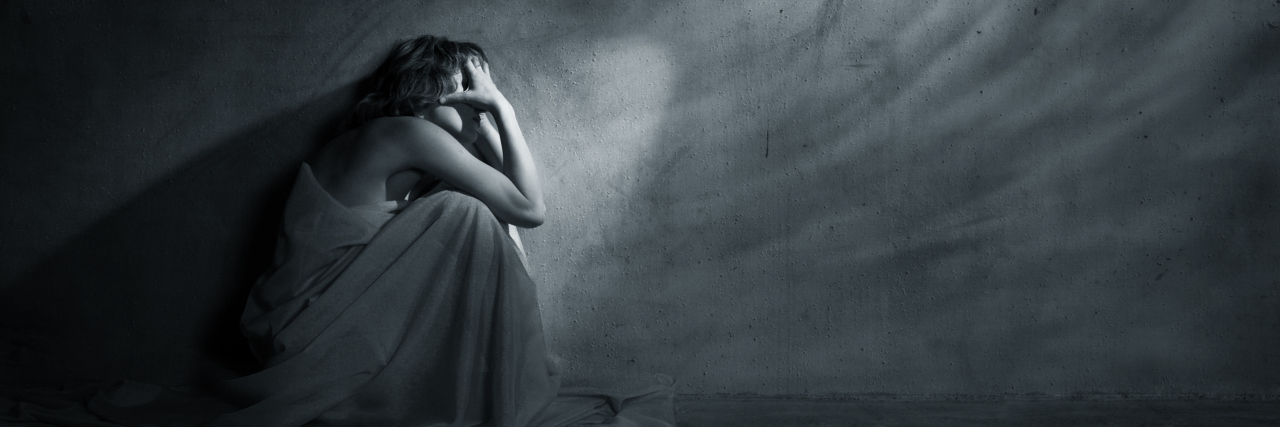 woman covering face with hands beside wall with windswept markings