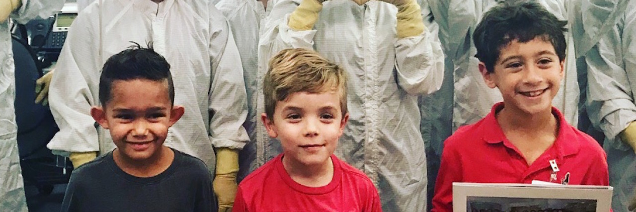 When My Family Met the Team That Created My Son's Heart Valve The three children and the team that created their heart valves behind them, making hearts with their hands.