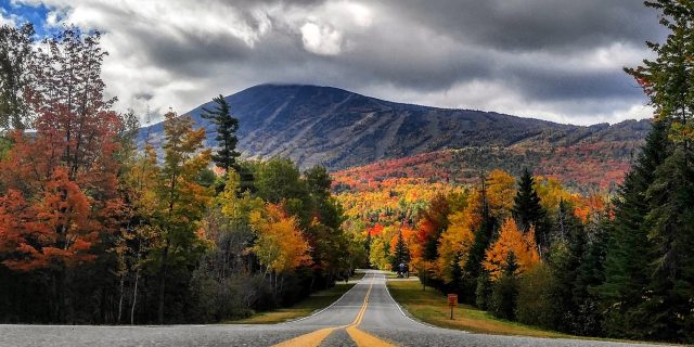 road leading through forests and mountains in maine with fall foliage