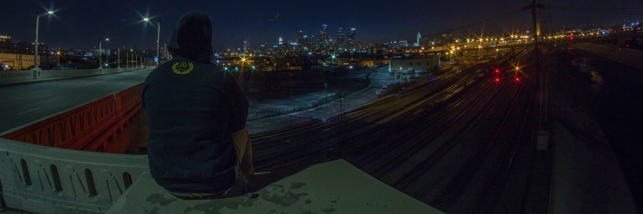 a man sits on a bridge overlooking a city