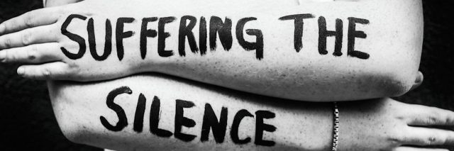 "suffering the silence" painted on a woman's arms