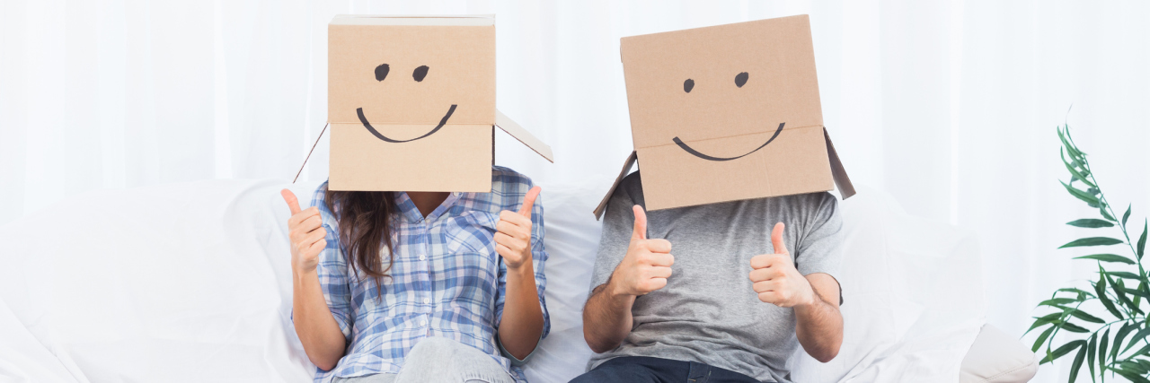 people sitting with boxes over their head and smiles drawn onto the boxes