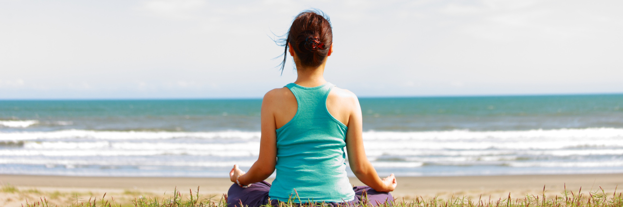 woman sitting alone on the beach looking at the ocean