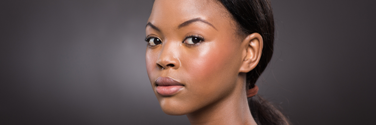 The Health Battle You Don’t See When You Judge My Outfit A beautiful African American looking at the camera with a serious expression.