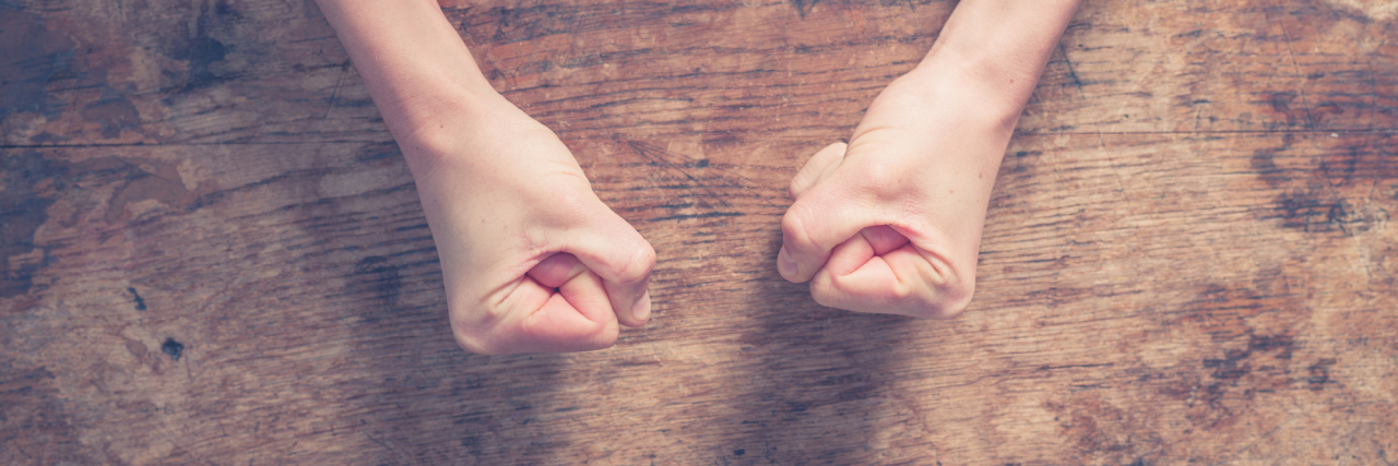 How I’m Learning It’s OK to Feel Anger Female fists clenched on a wooden table in anger