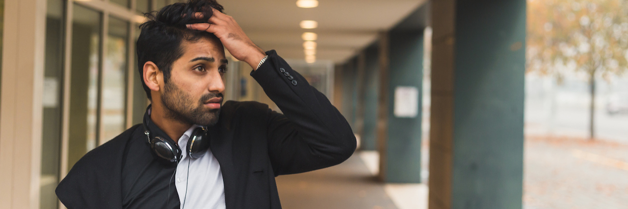 Initiating Conversations About Mental Illness With a Tattoo in India Man standing, running his fingers through his hair