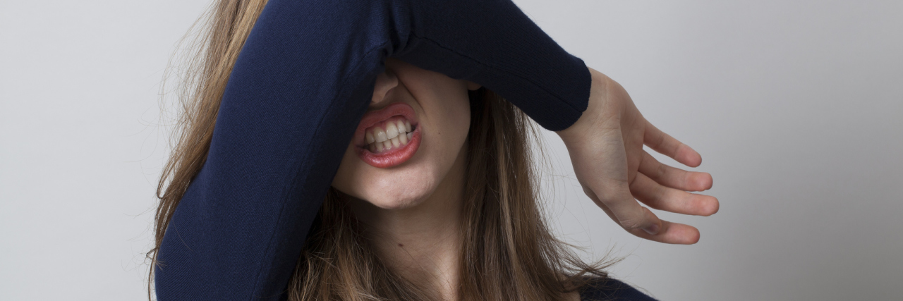 The Awkwardness of Telling People I Have Multiple Sclerosis woman hiding her face with her arm