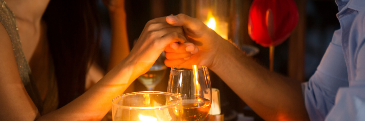 Romantic couple holding hands over candlelight during romantic dinner.