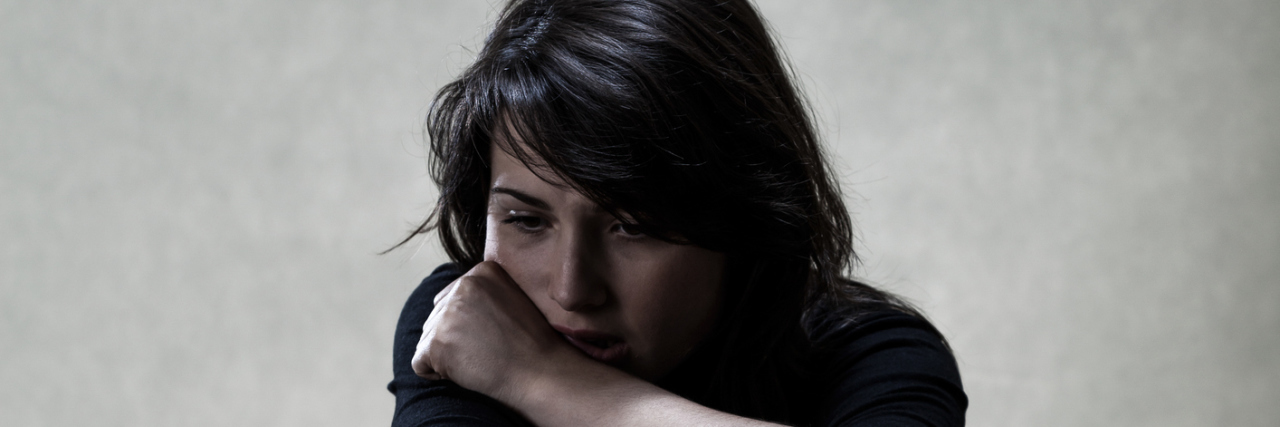 7 Things I Wish I Knew When I Received My Ulcerative Colitis Diagnosis A sad woman sitting on the floor with a solemn expression on her face.