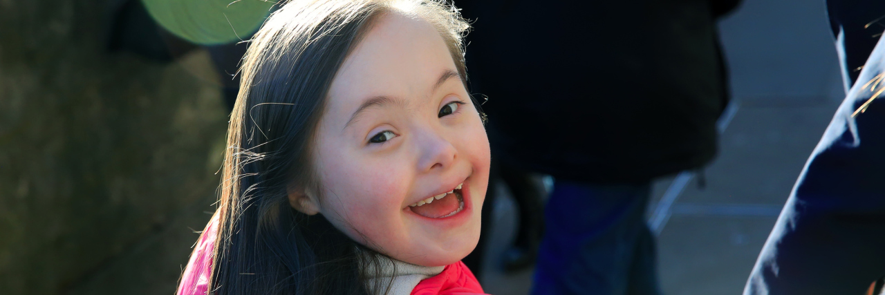 A Friend Asked What to Say When Her Son Said, 'What's Wrong With Her?' Little girl with Down syndrome smiling at camera walking away