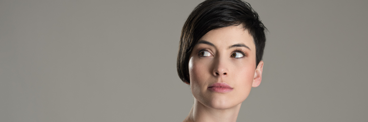 It's OK If Your Chronic Illness Story Isn't a 'Feel-Good Story' A woman with dark hair look over her shoulder.