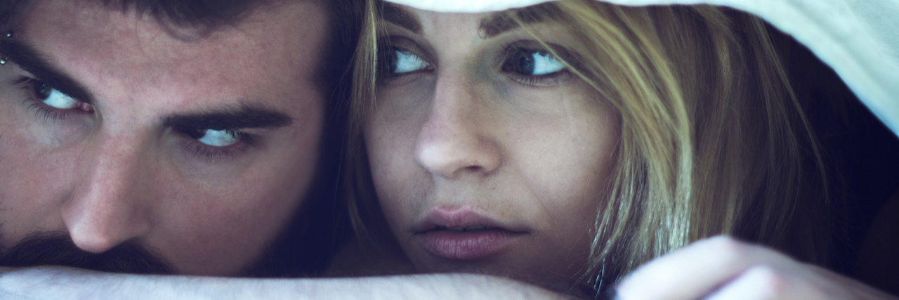 Couple laying in bed looking sad