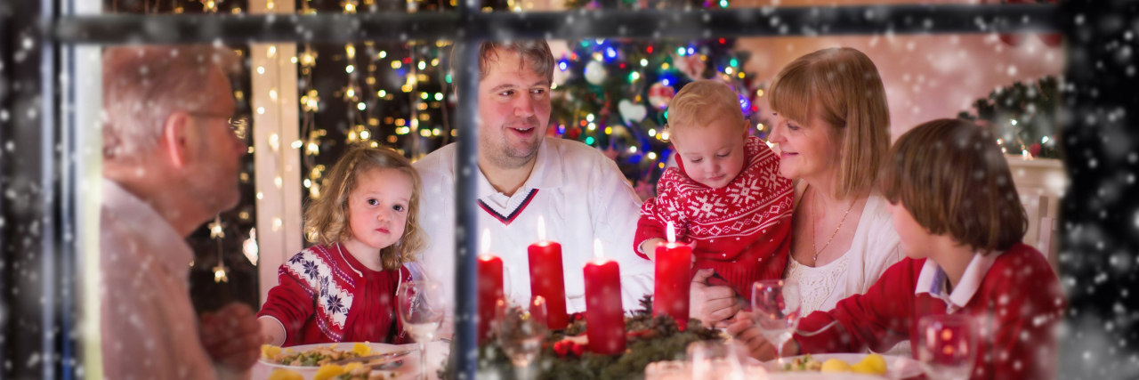 A photo looking into a window of a family at Christmas time.