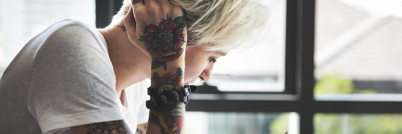 How Dyeing My Hair and Getting Tattoos Helps My Mental Illnesses woman with tattoos painting