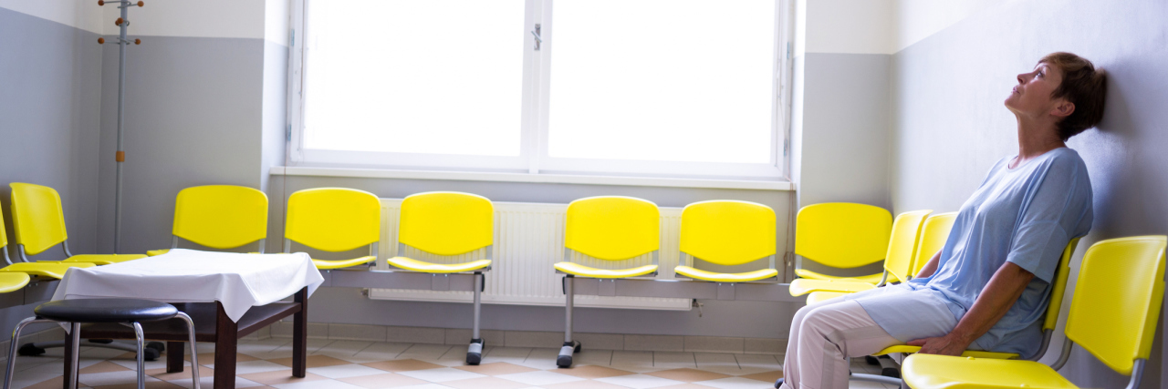 patient sitting alone in waiting room yellow chairs