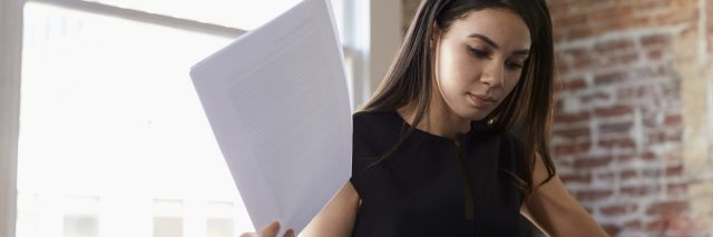 Businesswoman Making Notes On Document In Office
