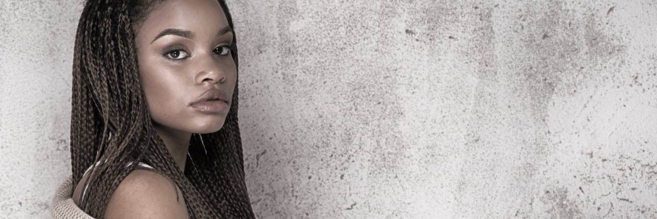 The Loneliness of Living With Chronic Illness woman standing alone against a gray wall