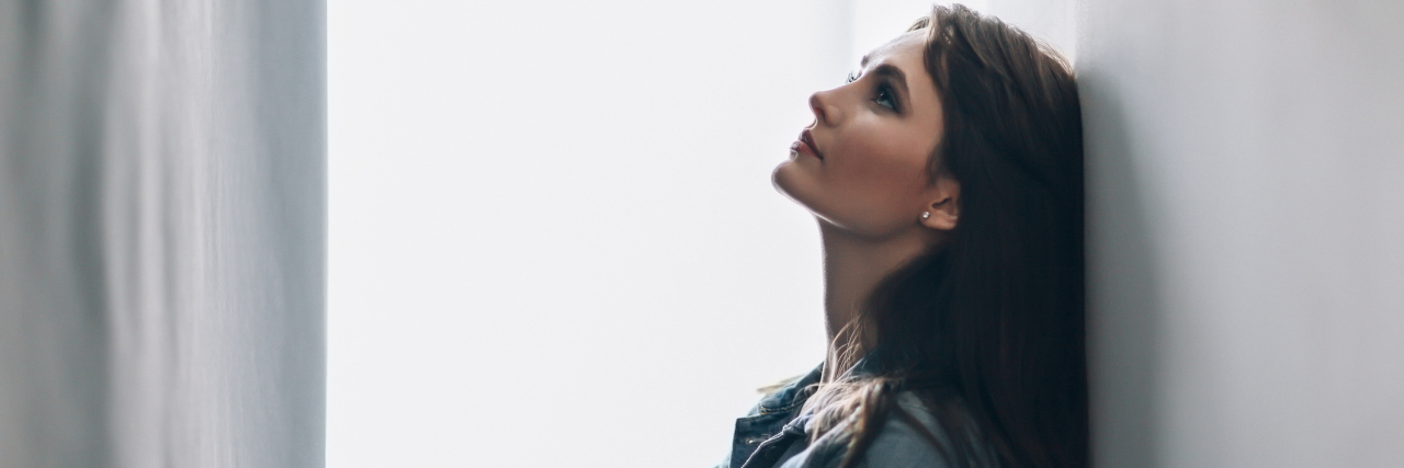 The Chronic Illness Edition of 'Would You Rather' Woman leaning against a wall, thinking.