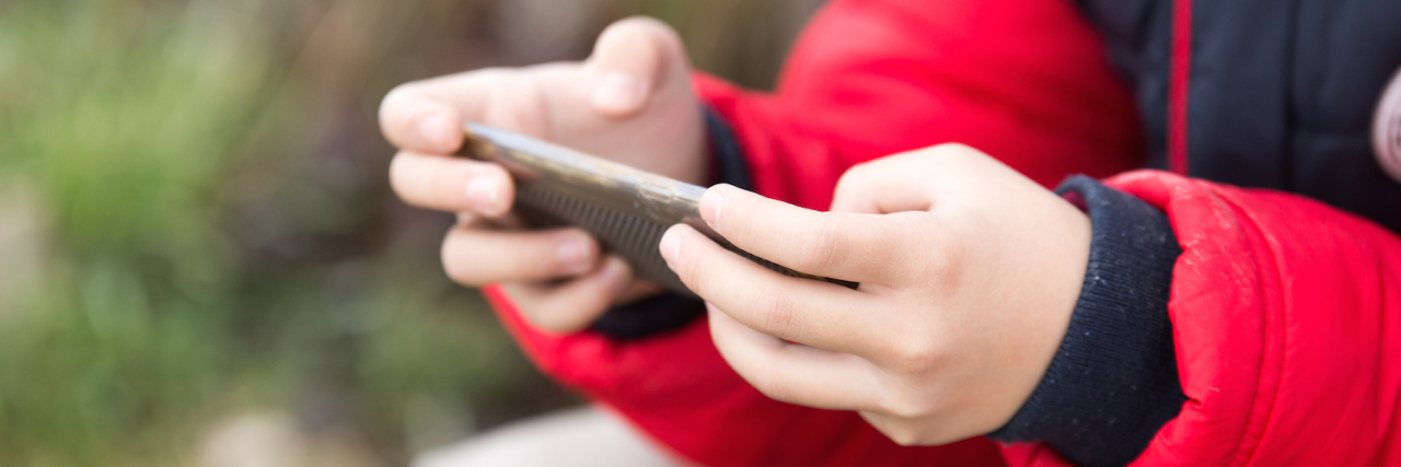 boy holding cell phone outdoors