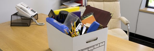 Box of office supplies on desk.