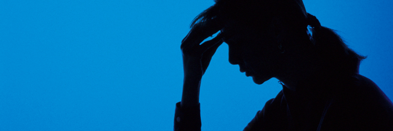 silhouette of a woman holding her head against a blue background