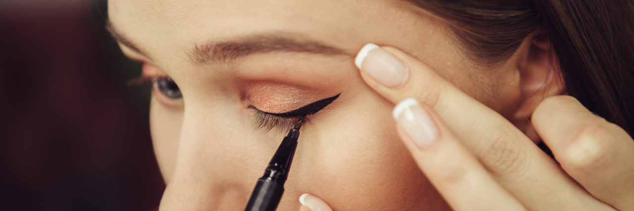 woman putting on eyeliner