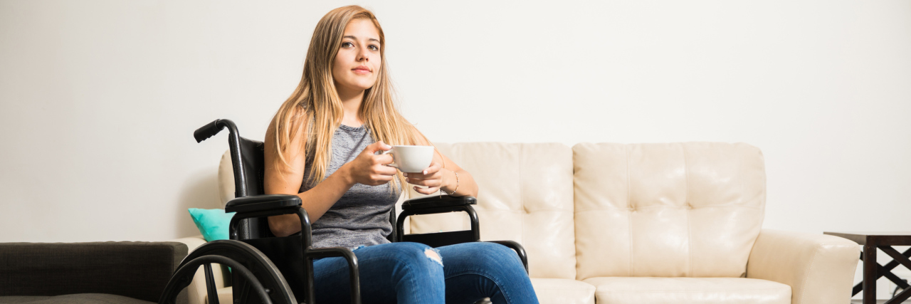 This Phrase Reminds Me That I'll Always Be in Pain A woman sitting in a wheel chair, drinking a cup of coffee.