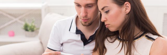 couple looking at negative pregnancy test result