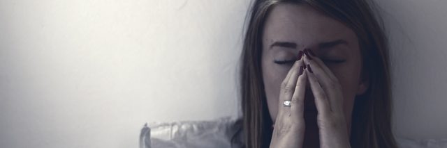 A woman sitting in bed in pain.