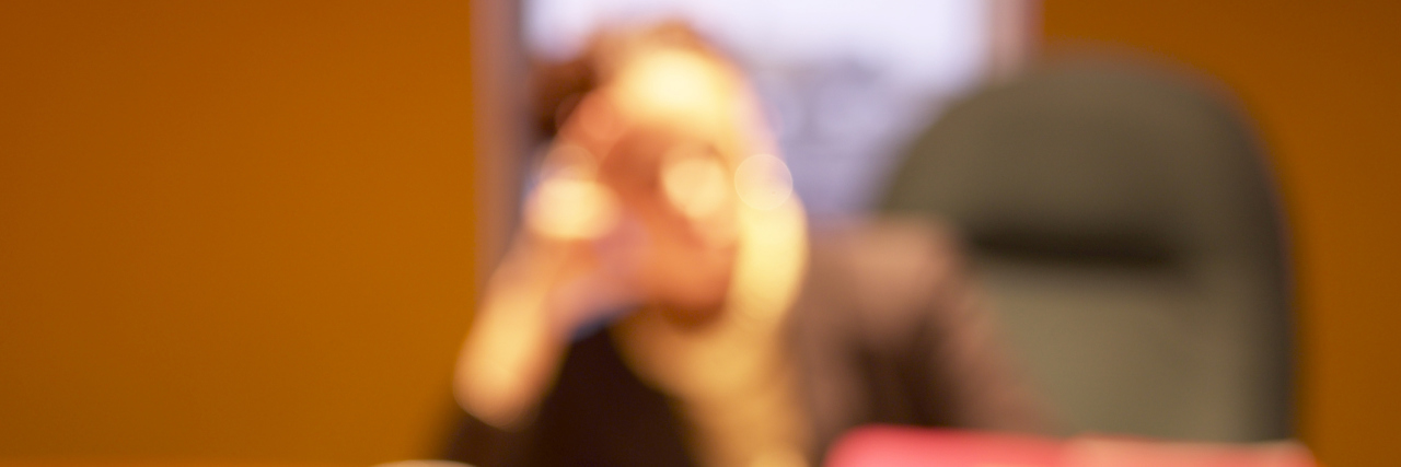 blurred image of woman sitting at her desk